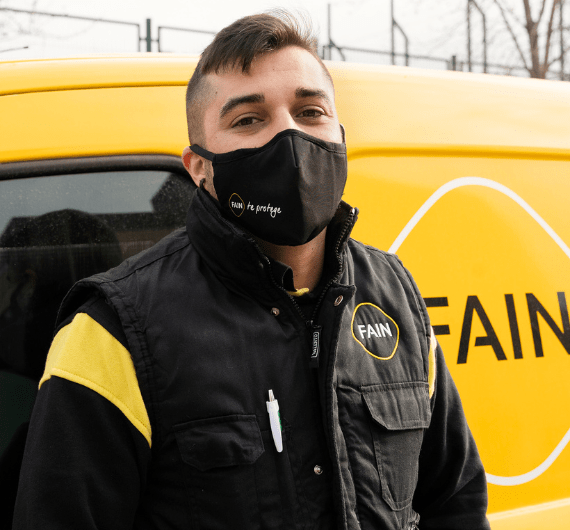 Technicien de maintenance d'ascenseur devant sa voiture portant un masque.