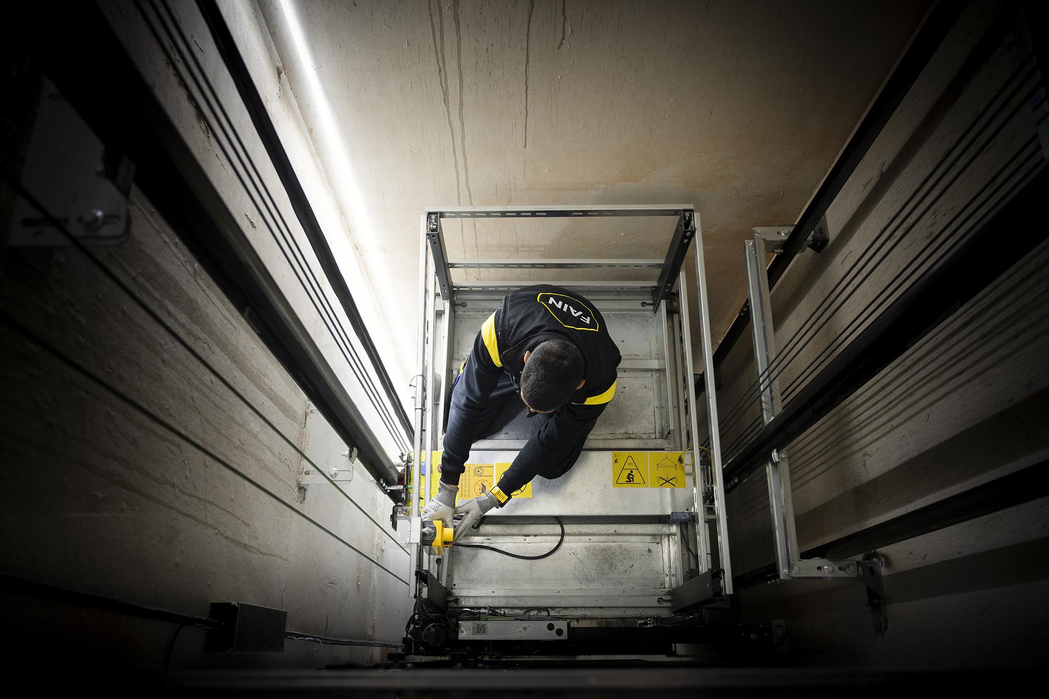 Image d'un technicien travaillant dans une cage d'ascenseur.