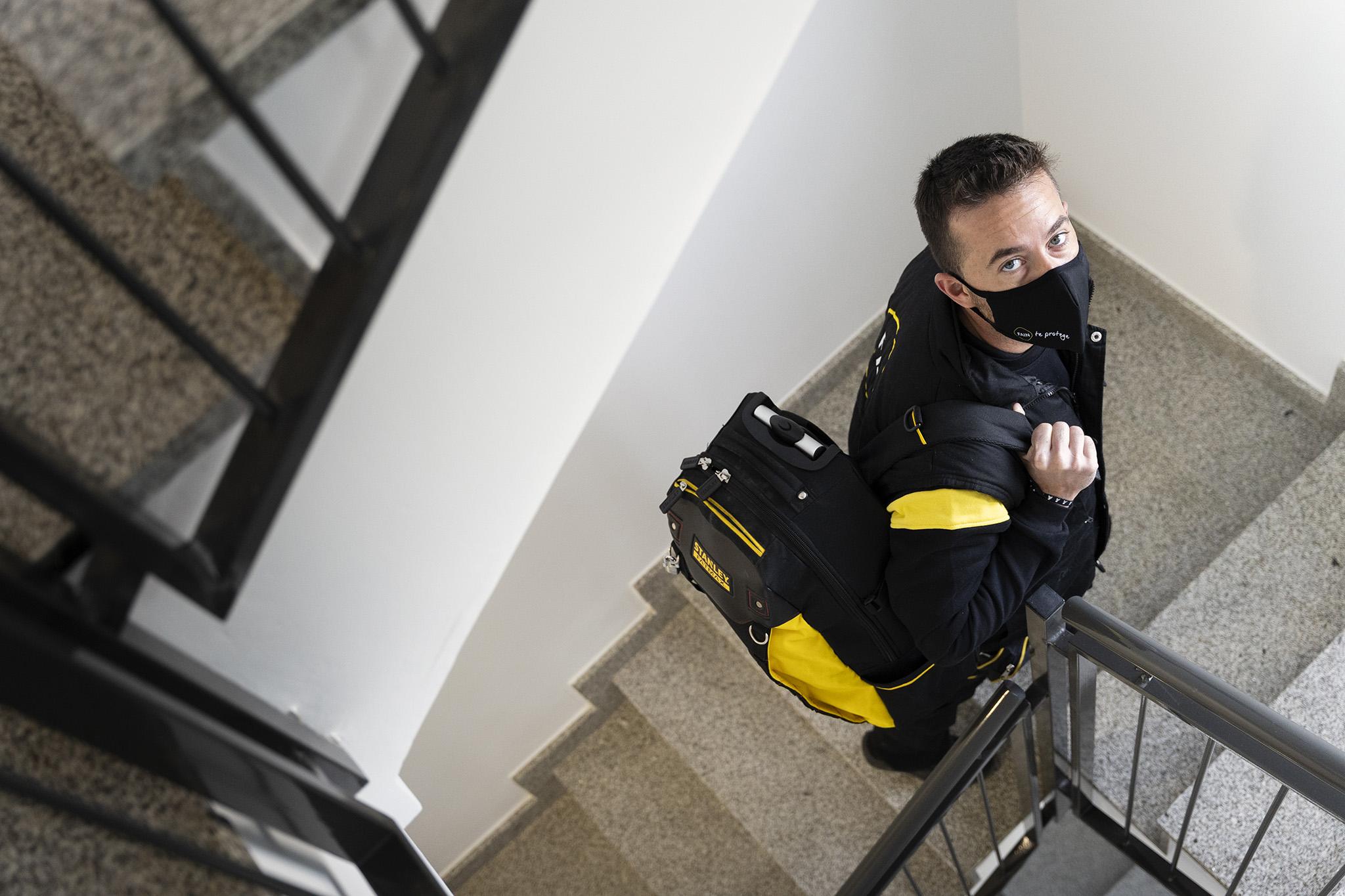 Technicien FAIN montant dans des escaliers.