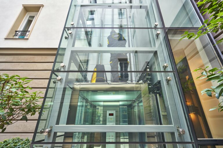 un technicien qui s'occupe de reparer un ascenseur exterieur vitré moderne